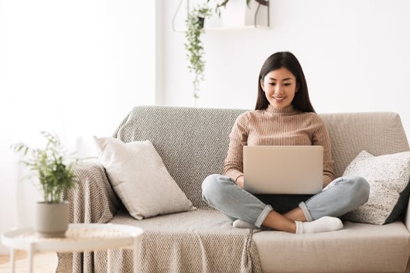 Girl on couch with laptop crossed legs