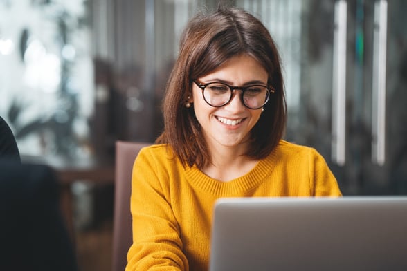 Happy woman in office looking at computer in glasses-1