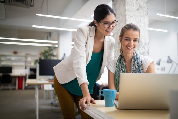 Two women working at computer together in office