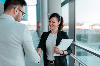 Woman in business outfit with clipboard shaking hands