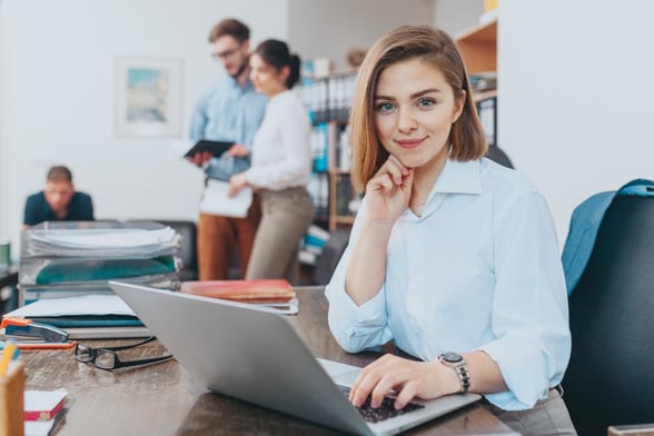 business woman on computer looking at camera in office