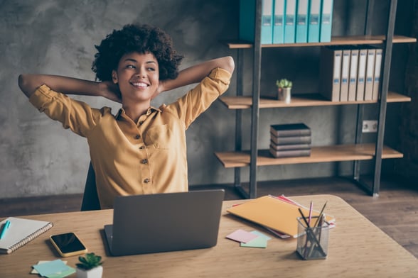 woman in home office sitting back in chair